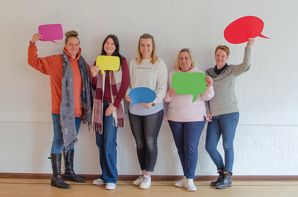 Fünf Mitarbeitende der Dachstiftung Diakonie mit bunten Sprechblasen