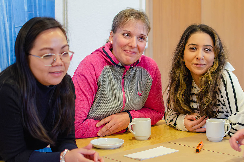 Drei Teilnehmende bei einem Workshop zur Feedbackkultur mit Kaffeetassen